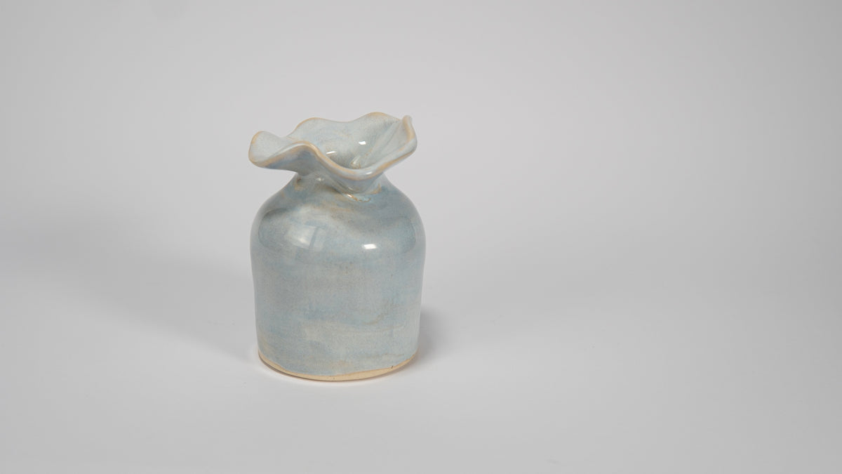 Small ceramic vase with a textured surface on a plain background