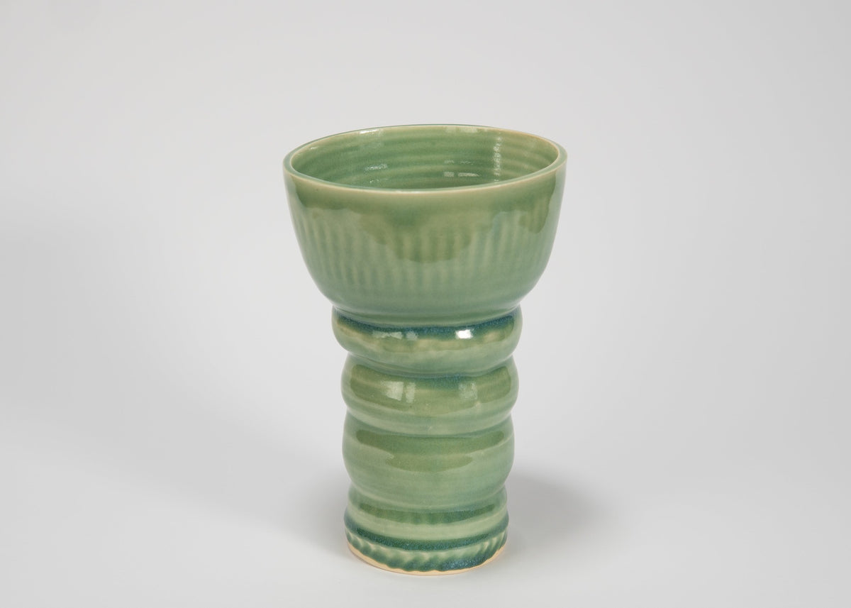Green ceramic vase with textured design on a white background