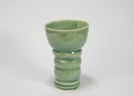 Green ceramic vase with textured design on a white background